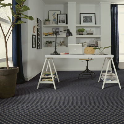 Minimalist home office with navy blue patterned carpet, white desk, and natural wood accents, showcasing the carpet's texture and design.